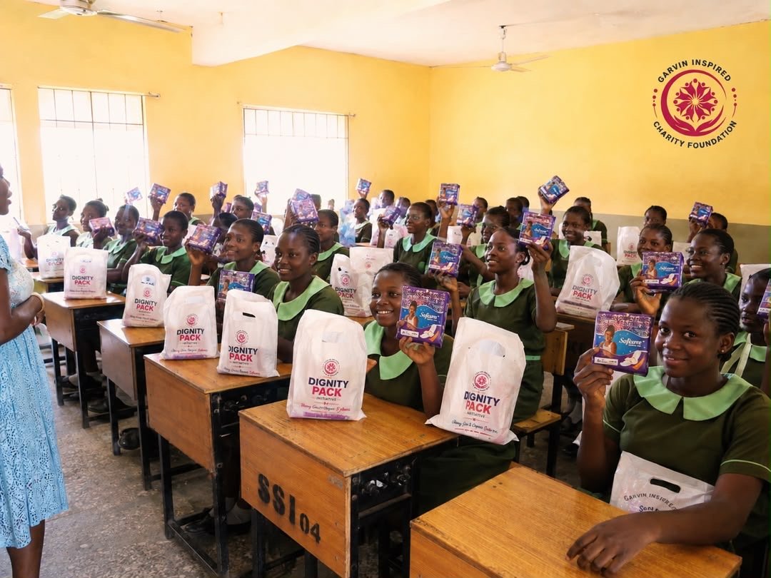 Schoolgirls in classroom holding Dignity Pack kits
