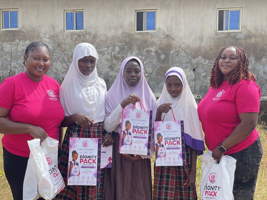 Volunteers with schoolgirls holding Dignity Pack bags